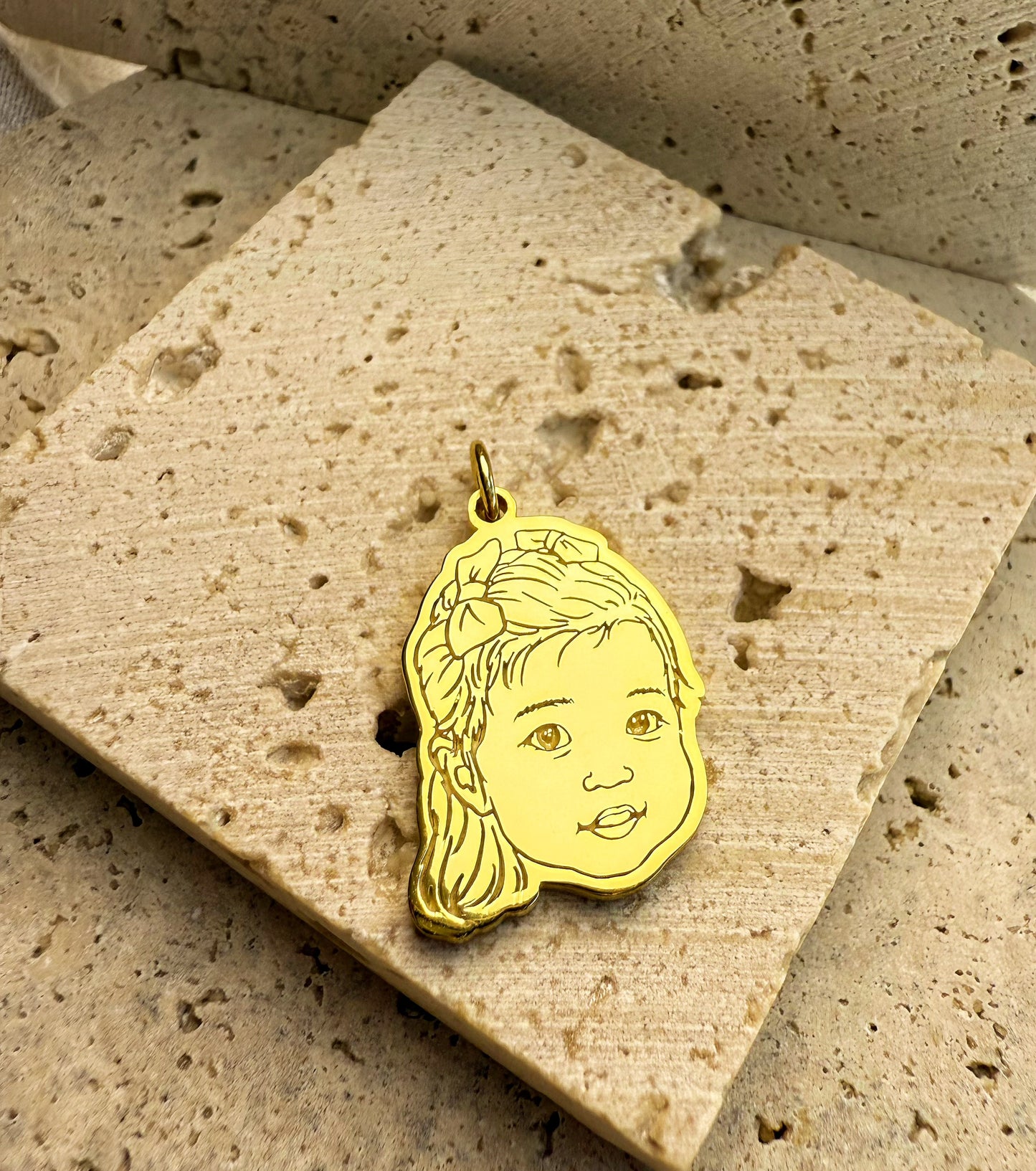 18k Gold Vermeil custom 3D engraved baby portrait pendant on a textured stone surface