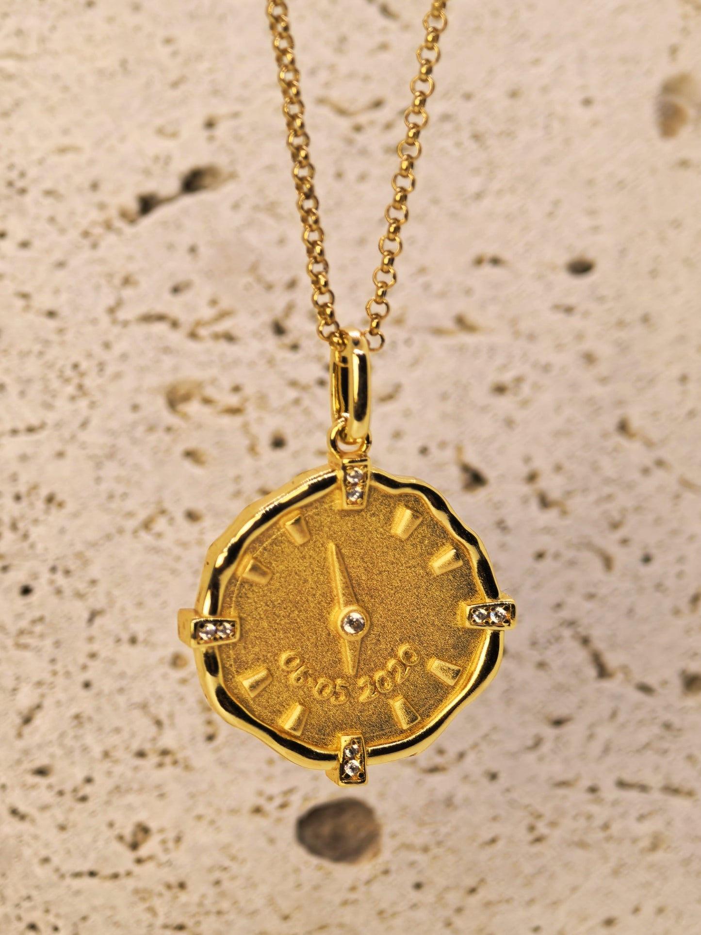 18K_Gold_Vermeil_Matte_Finish_custom_necklace_with_baby_birthtime_3D_engraved_on_a_clock displayed on a textured background