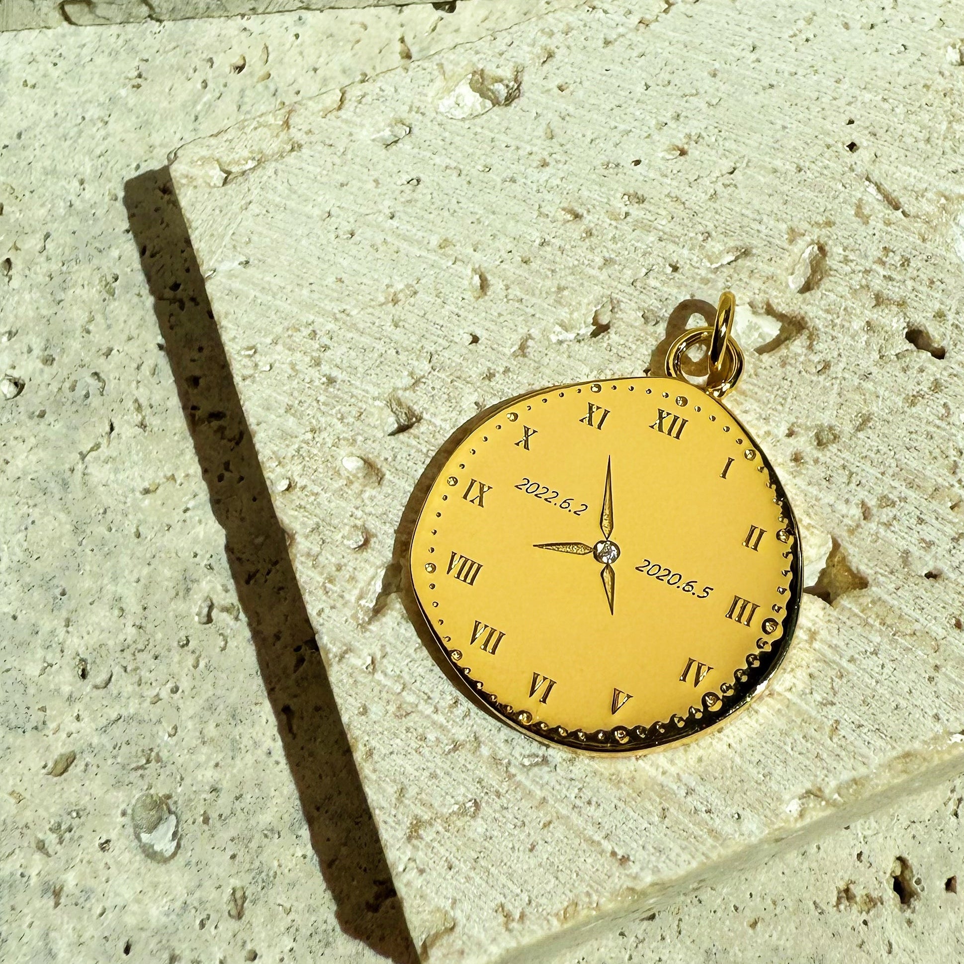 18K Gold Vermeil personalize clock designed with newborn birth time engraved pendant on a textured stone surface