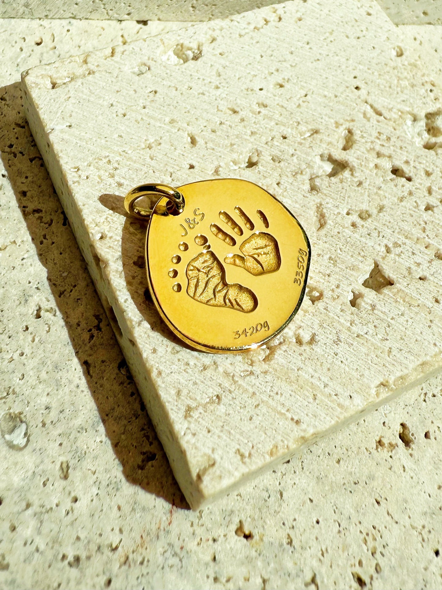 18k Gold Vermeil custom pendant with baby hand and footprints on a textured stone surface