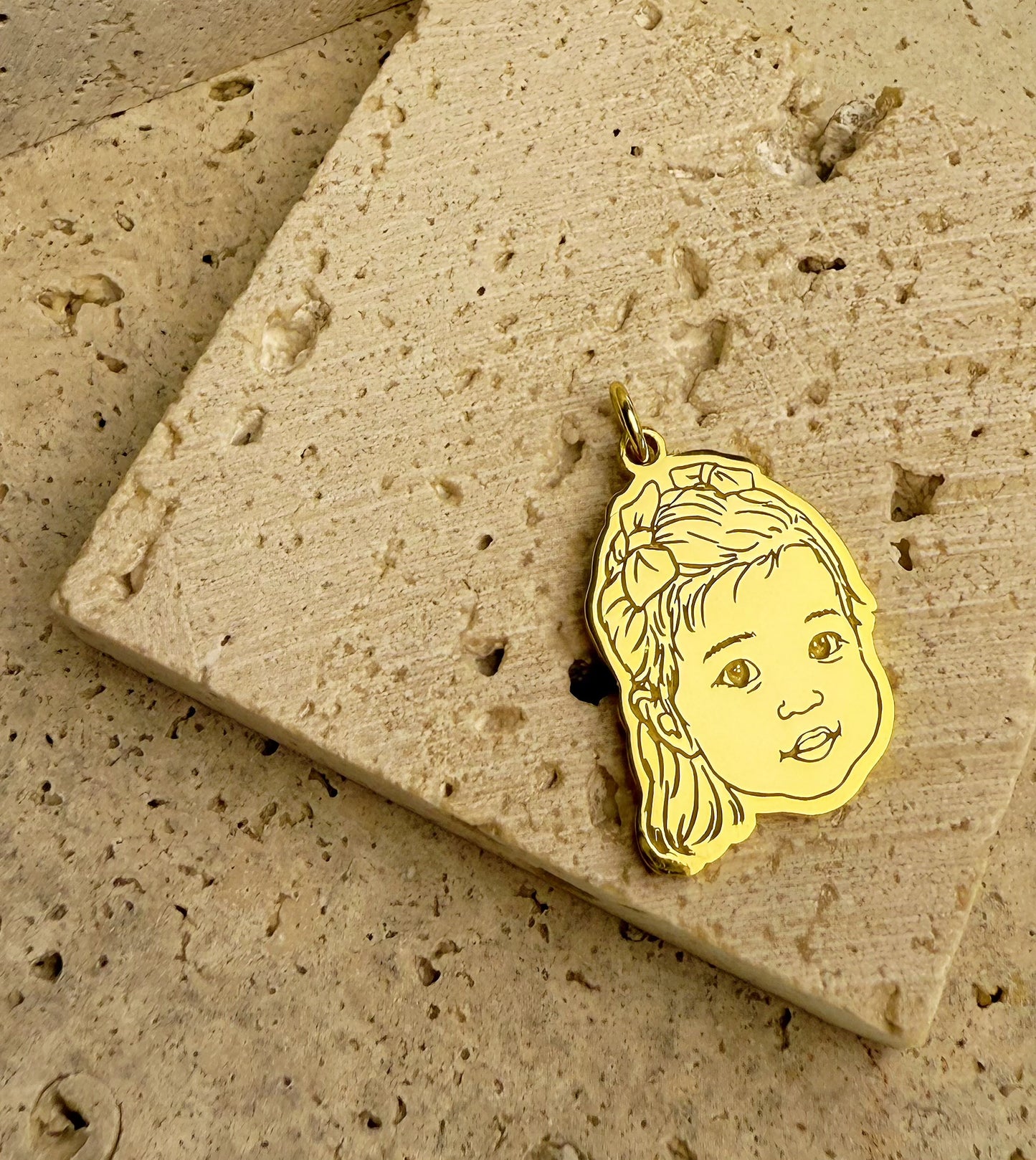 18k_Gold_Vermeil_personalize_3D_engraved_baby_portrait_pendant on a textured stone surface