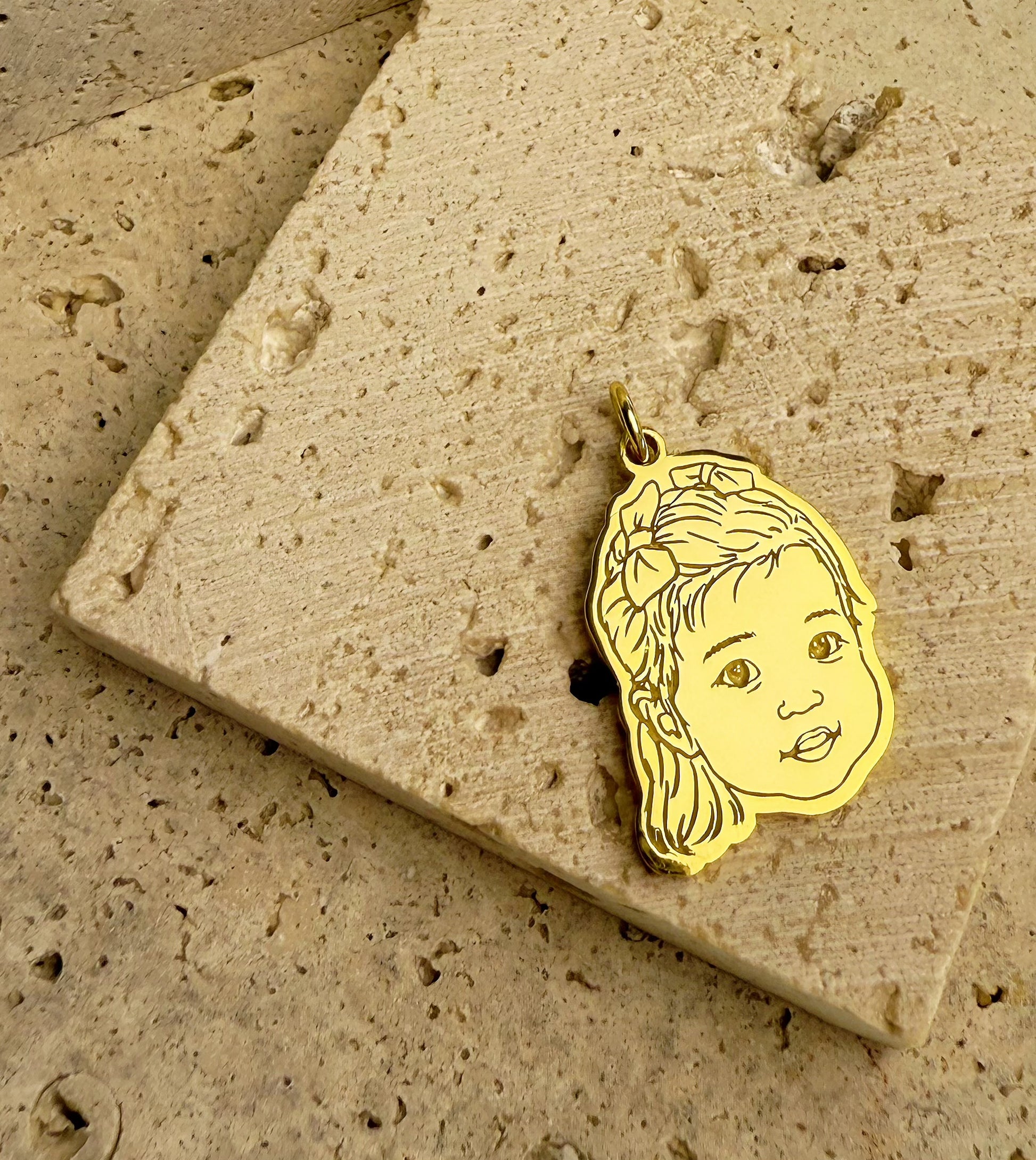 18k_Gold_Vermeil_personalize_3D_engraved_baby_portrait_pendant on a textured stone surface